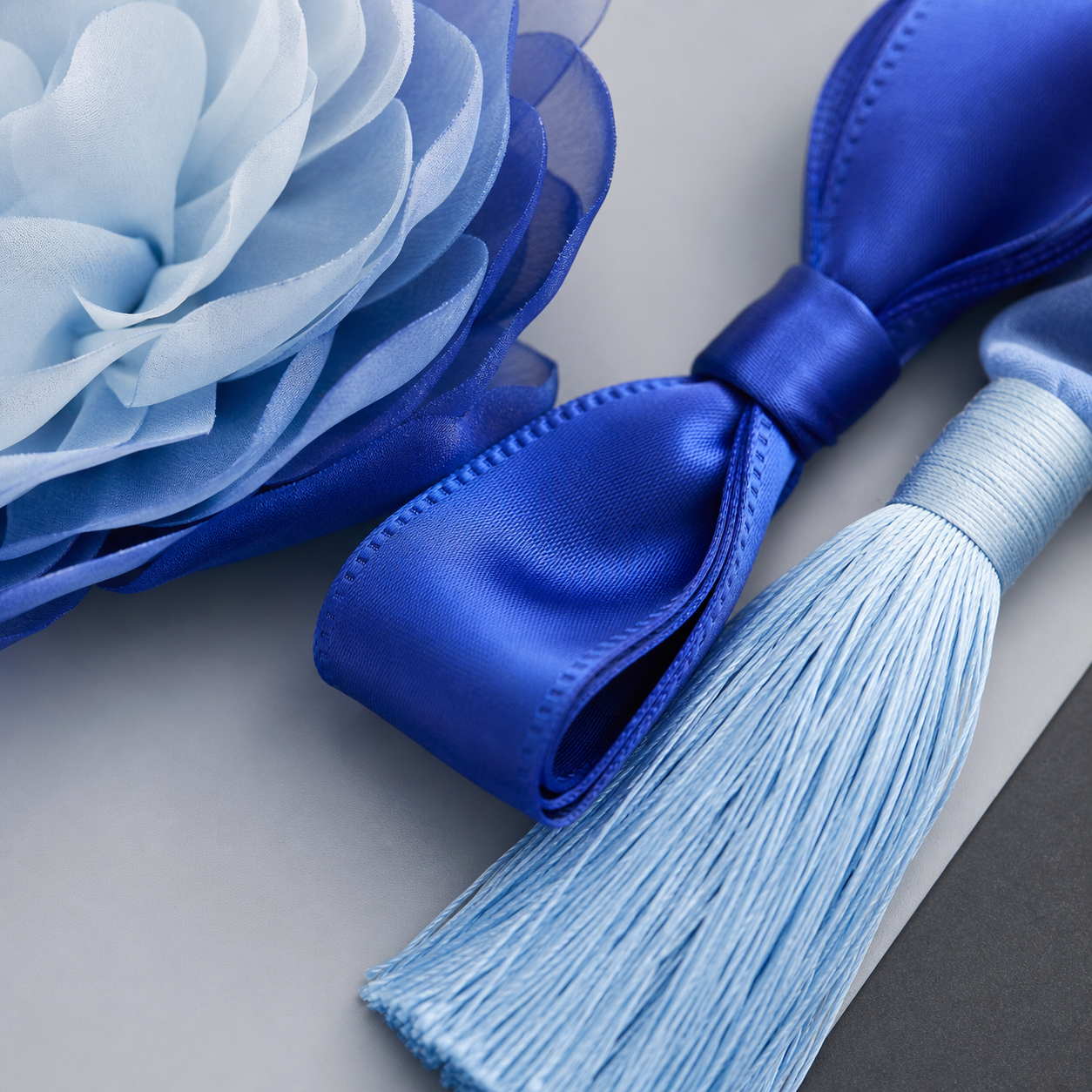 Layered blue fabric petals royal blue satin bow and pale blue silk tassel texture